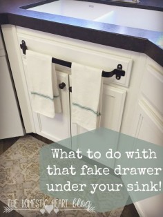 What to do with that fake drawer under your kitchen sink. Kitchen cabinet towel bar and other kitchen hacks at the Domestic Heart blog.