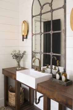 Beautiful rustic industrial bathroom design. That mirror is incredible looking on the plank wood wall!