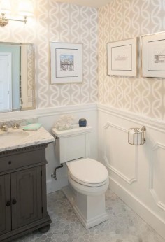 Chic powder room features top half of walls clad in beige geometric wallpaper and lower walls clad in decorative moldings lined with a gray vanity, Restoration Hardware St.