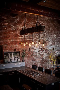 Exposed duct pipes, brick walls and lighting create a distinct modern industrial style in the kitchen