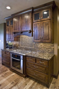 Like the tone of the Rustic Knotty Alder Kitchen Cabinets, would prefer Shaker design. Like the style of glass in the cabinet doors, the covered hood, and the over all craftsman details including the ceiling molding. . Nice countertops.