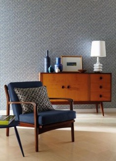 Midcentury indigo chair and teak cabinet against the wallpaper.