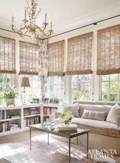 Neutral, half wall corner bookcase, woven window shades, ornate gold chandelier