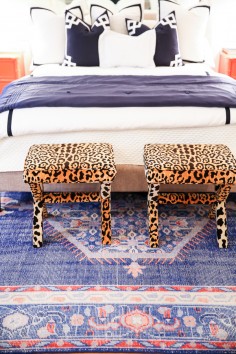 Preppy eclectic bedroom with royal blue and red rug, leopard stools, navy and white bedding