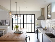 Three pendant lights from West Elm are suspended over a knotty-surfaced farm table in the kitchen, one of the few holdovers from the homeowners' previous decor.